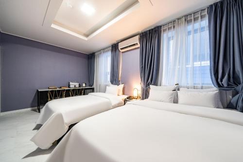 Sloth Hotel Gimhae في Gimhae: سريرين في غرفة مع جدران ونوافذ زرقاء