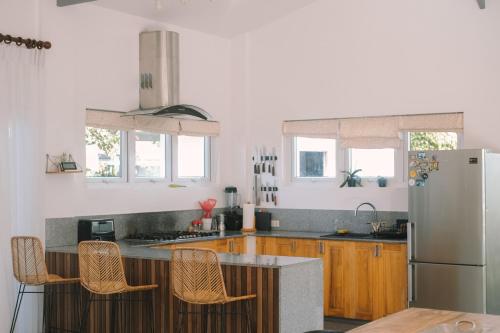 a kitchen with wooden cabinets and a white refrigerator at Villa Aurora Siargao - Villa 1 in General Luna