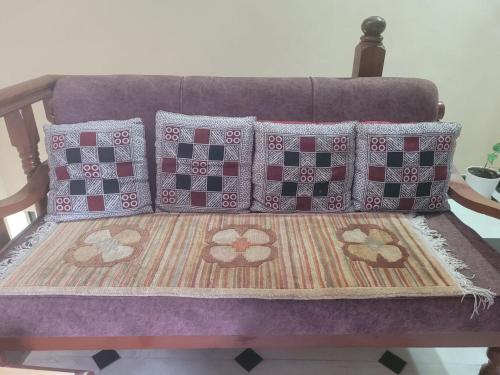 a purple couch with four pillows on it at Ishani House in Bharatpur