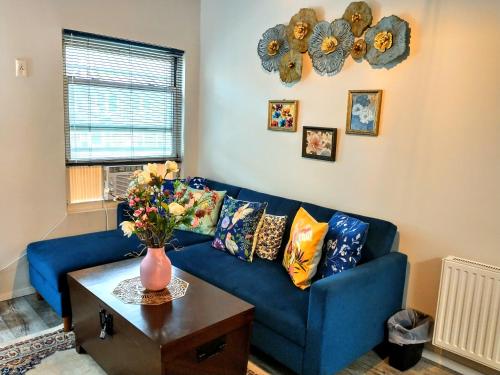 un sofá azul en una sala de estar con un jarrón de flores en Explore New York from Queens, en Queens