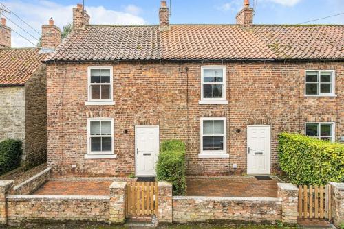 a brick house with white doors and a fence at Ivy Cottage Nestled Near The White Horse in York