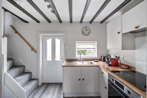 una cocina con armarios blancos y una escalera en Ivy Cottage Nestled Near The White Horse, en York