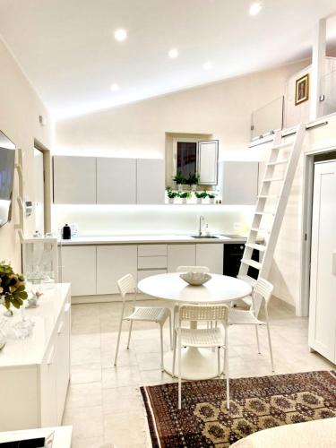 a white kitchen with a white table and chairs at Loft Agata - host Marco cell.339/3860587 in Polistena