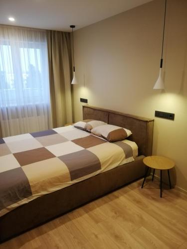 a bedroom with a bed with a table and a window at Windy City apartments in Liepāja