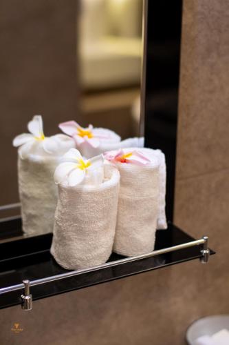 three rolls of towels on a shelf in a bathroom at Tharusha Hotel in Galle