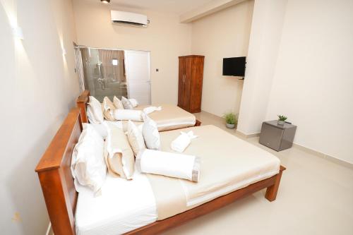 two beds with white sheets and pillows in a room at Tharusha Hotel in Galle