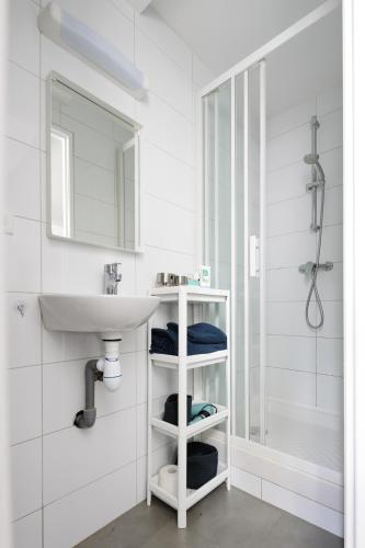 une salle de bain blanche avec un lavabo et une douche dans l'établissement Charmant studio, au cœur de la ville de Riom, à Riom