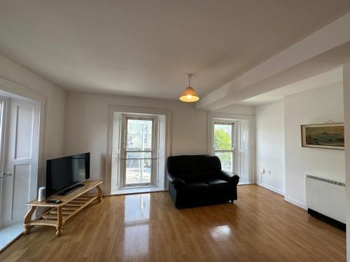 uma sala de estar com uma cadeira preta e uma televisão em Bridge View Apartment em Waterford