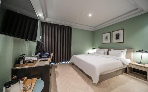 um quarto com uma cama e uma secretária com um computador em Brown Dot Hotel Sajik Baseball Stadium em Busan