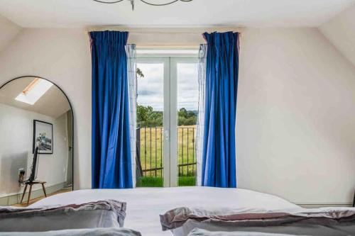 a bedroom with blue curtains and a large window at Elmcroft, Large House with Shepherds Hut in Gillingham