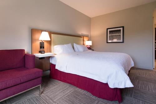 a hotel room with a bed and a red chair at Hampton Inn and Suites Fayetteville, NC in Fayetteville