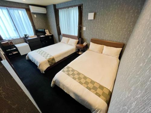 una camera d'albergo con 2 letti e una scrivania di NARITA HOTEL KAKUREGA - Vacation STAY 69221v a Narita