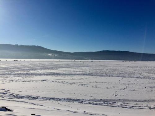 a snow covered beach with people in the distance at Lipno Villa Beach - Lipno Stausee - Lakeside in Loučovice