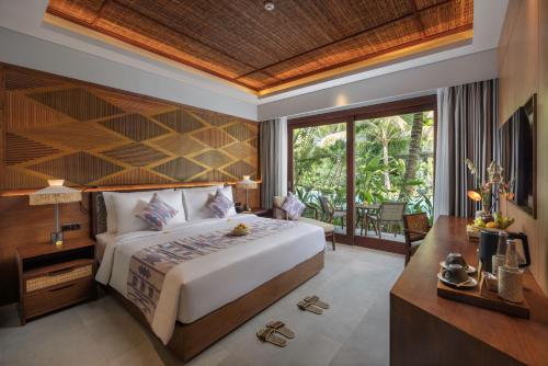 a bedroom with a bed and a desk and a window at The Hava Ubud A Pramana Experience in Ubud
