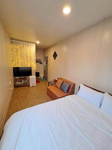 1 dormitorio con 1 cama blanca grande y 1 sofá en 舞浪海景旅店, en Xiaoliuqiu