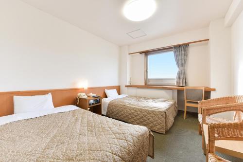 a hotel room with two beds and a desk and a window at Kitami Plaza Hotel in Kitami