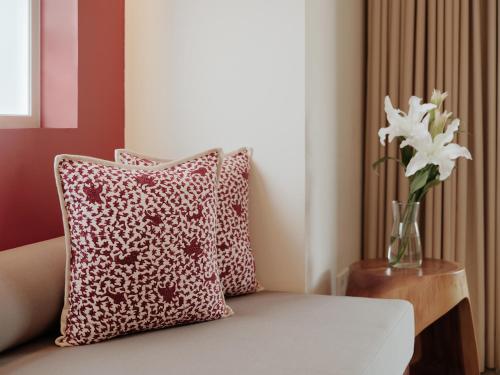a vase of flowers sitting on a couch with a pillow at Chesa Canggu in Canggu