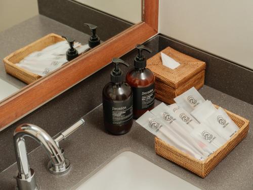 - un lavabo dans la salle de bains avec 2 bouteilles de savon et des serviettes dans l'établissement Chesa Canggu, à Canggu