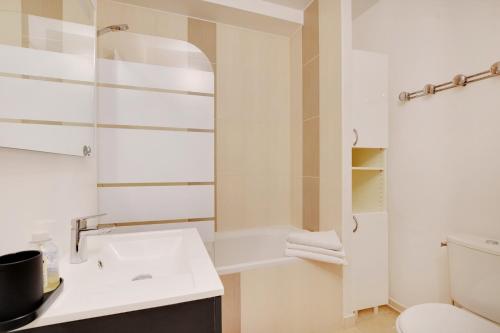 a white bathroom with a toilet and a sink at Maison de la Radio - Tour Effeil in Paris