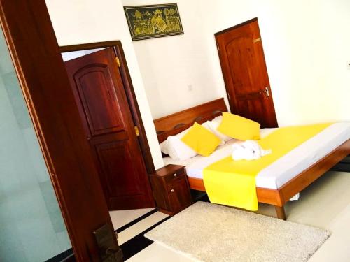 a bedroom with a bed with yellow and white pillows at Lake View Resort in Pamunugama
