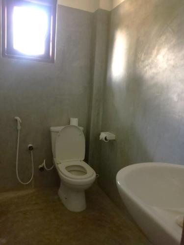 a bathroom with a toilet and a sink and a window at Lake View Resort in Pamunugama
