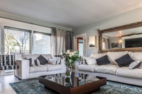 una sala de estar con 2 sofás blancos y un espejo en Magnífica Casa Familiar en Moralzarzal Madrid, en Moralzarzal