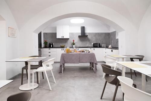 una cucina e una sala da pranzo con mobili bianchi e tavoli di Bohoostel a Bologna