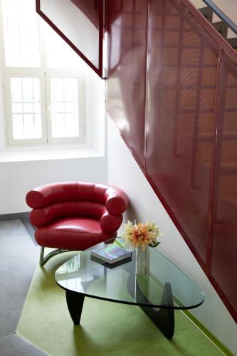 a red chair and a glass table in a room at Bohoostel in Bologna