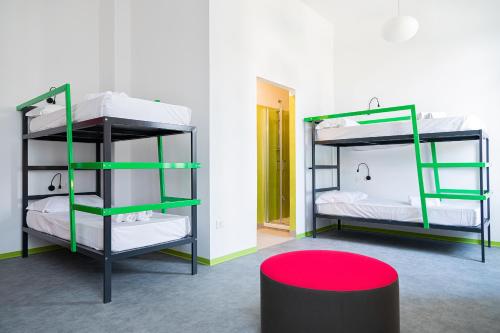 2 łóżka piętrowe w pokoju z czerwonym stołkiem w obiekcie Bohoostel w Bolonii