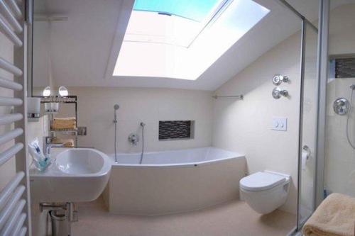 ein Badezimmer mit einer Badewanne, einem WC und einem Dachfenster in der Unterkunft Sonnentau -909- in Mittenwald