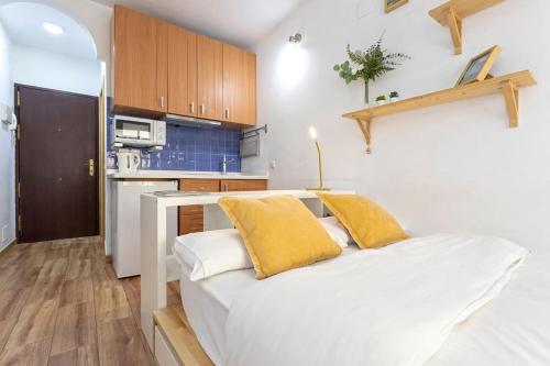 Un dormitorio con una cama blanca con almohadas amarillas. en MÁLAGA CENTER, MALAGUETA BEACh, en Málaga