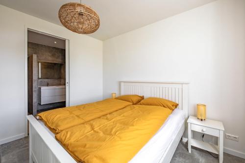 1 dormitorio blanco con 1 cama grande con sábanas amarillas en De Bunders Texel, en De Cocksdorp