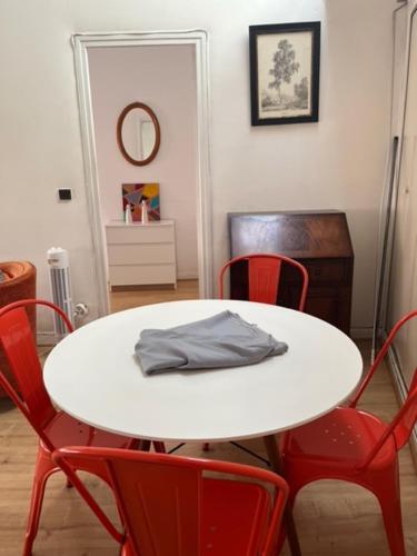 - une table blanche avec des chaises rouges et une chemise grise dans l'établissement Marvejol T2, à Toulouse