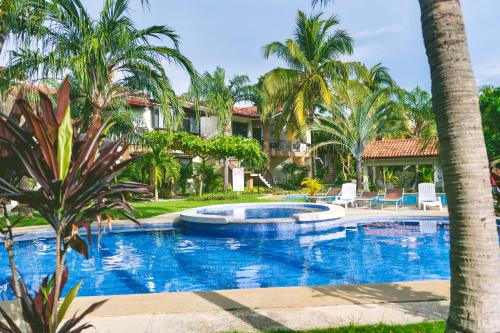 a pool in front of a house with palm trees at The Beach House Ground Floor Condo in Coco