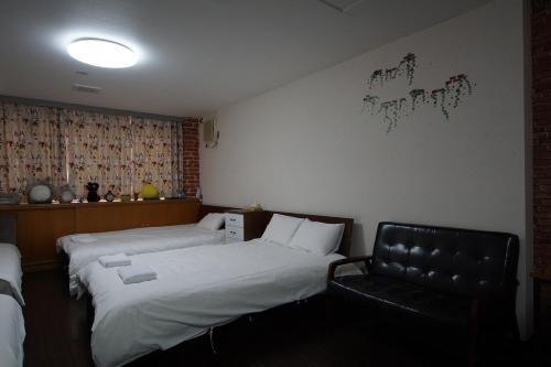 a bedroom with two twin beds and a chair at TokyoGuest Akihabara in Tokyo