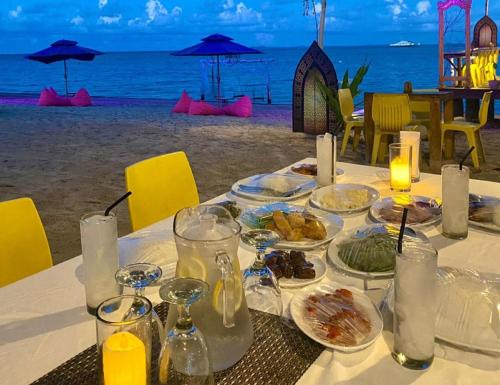 - une table avec des assiettes de nourriture sur la plage dans l'établissement Marjoly Beach Resort, à Telukbakau
