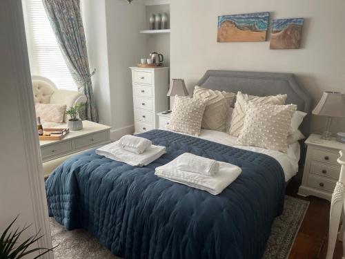 a bedroom with a blue bed with towels on it at The Captain's House in Looe