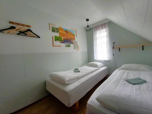 2 camas en una habitación pequeña con ventana en Húsavík Green Hostel en Húsavík