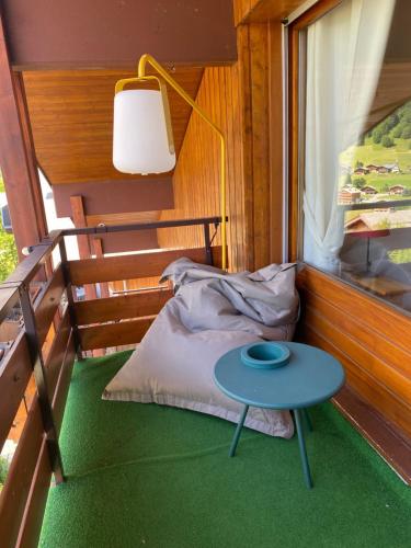 Zimmer mit einem Bett und einem Tisch auf dem Balkon in der Unterkunft Charmant appart style chalet, simple et soigné in Le Grand-Bornand