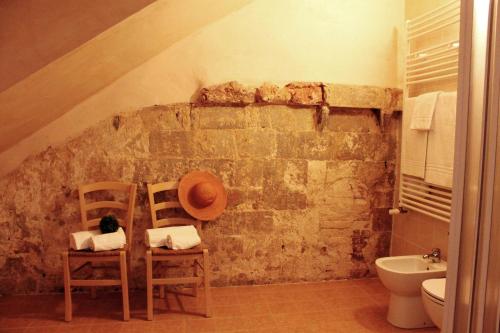 a bathroom with two chairs and a stone wall at Ostello Contessa Ava dei Lambardi in Monteriggioni