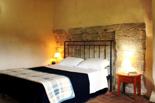 Ostello Contessa Ava dei Lambardi في مونتيريجيوني: غرفة نوم بسرير وجدار حجري