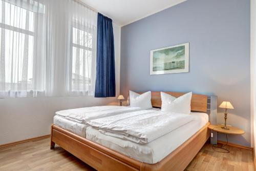 een slaapkamer met een groot bed met witte lakens bij Villa Sabinium in Heringsdorf