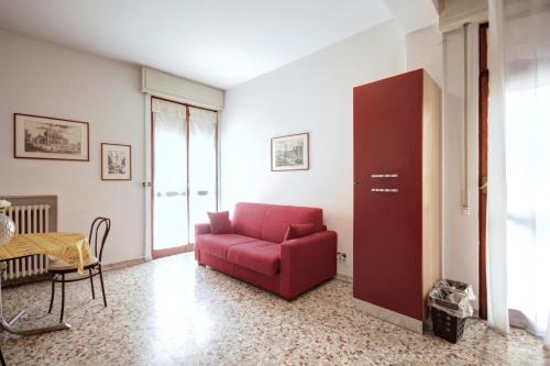 sala de estar con silla roja y mesa en MilanRentals - Teodorico Apartment, en Milán
