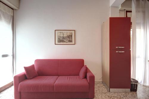 a living room with a red couch and a cabinet at MilanRentals - Teodorico Apartment in Milan