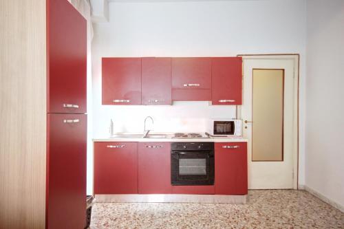 cocina con armarios rojos y microondas en MilanRentals - Teodorico Apartment, en Milán