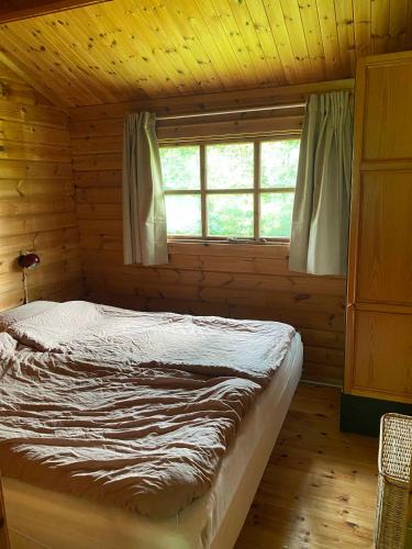een bed in een blokhut met een raam bij Family-friendly Cottage By Stoense Beach in Tranekær