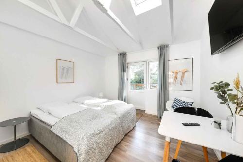 Schlafzimmer mit einem Bett, einem Schreibtisch und einem TV in der Unterkunft Summer Holiday Apartment At Beautiful Solgaarden in Svaneke