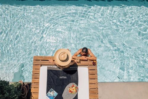 a man in a hat sitting in a pool at West East Suites in Imerovigli