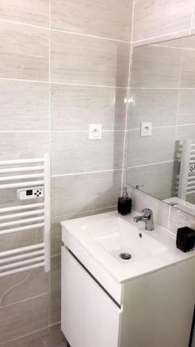 a white bathroom with a sink and a mirror at studio Pondichéry moderne in Morières-lès-Avignon