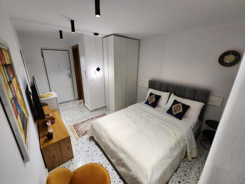 a small white bedroom with a bed and a mirror at Pietro Guesthouse 3 in Tirana